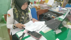"Guru dan Tumpukan Berkas Digital" — Potret seorang guru yang menghadap layar laptop penuh formulir dan unggahan platform, dengan ruang kelas kosong terlihat di belakangnya. Secara emosional menyentuh ironi antara tugas administratif dan panggilan mengajar.